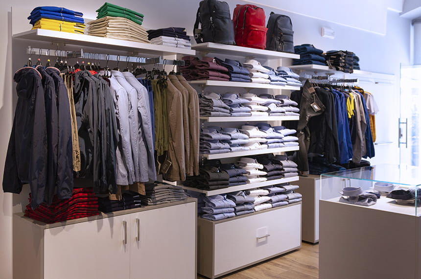 Arredo negozio abbigliamento uomo: vista su moduli a parete con mensole e appenderia a spalla