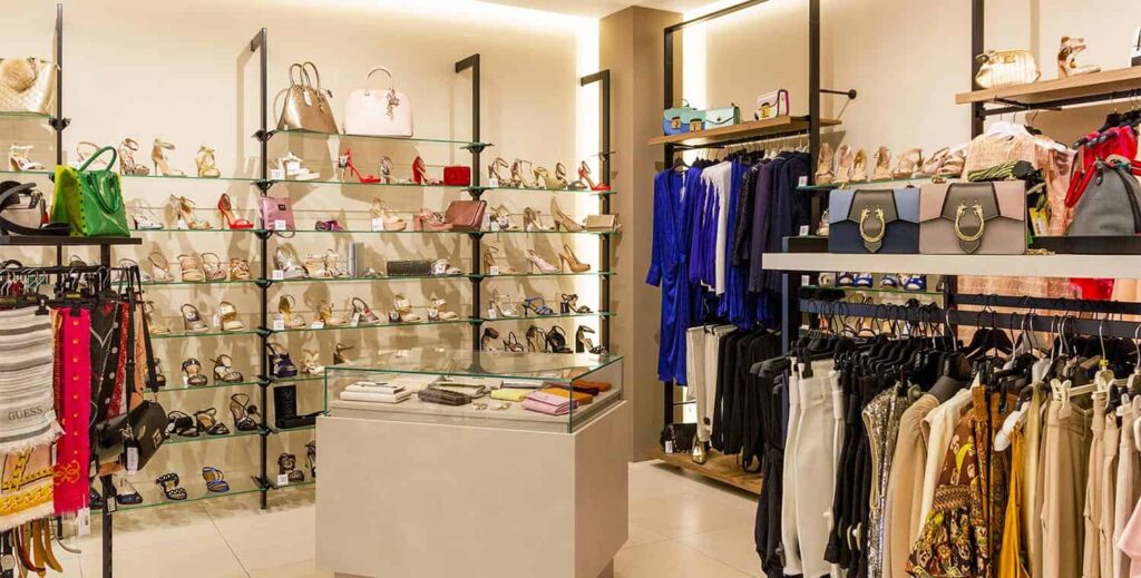 Vista su angolo arredamento negozio accessori moda scarpe borse con tavolo espositivo e pareti moderne