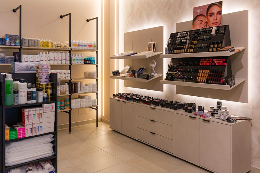 Arredamento profumerie: elemento espositivo per make up e struttura a parete dalla linea essenziale con ripiani